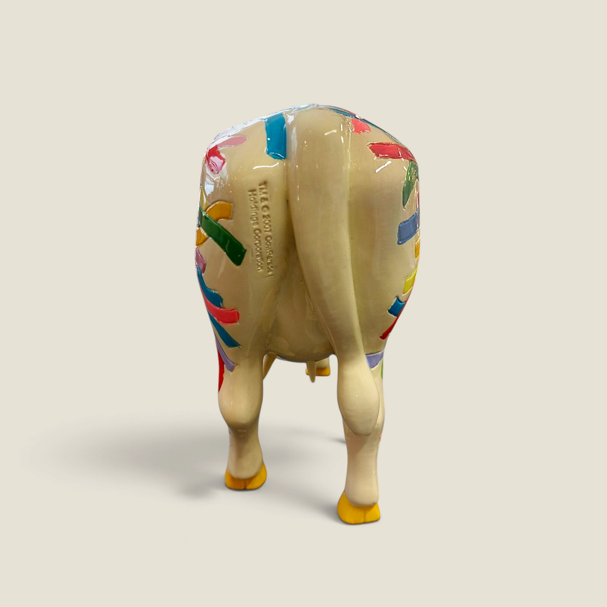 Vue arrière de la figurine vache Depuis des lustres en résine laquée avec motifs pop art multicolores sur fond crème