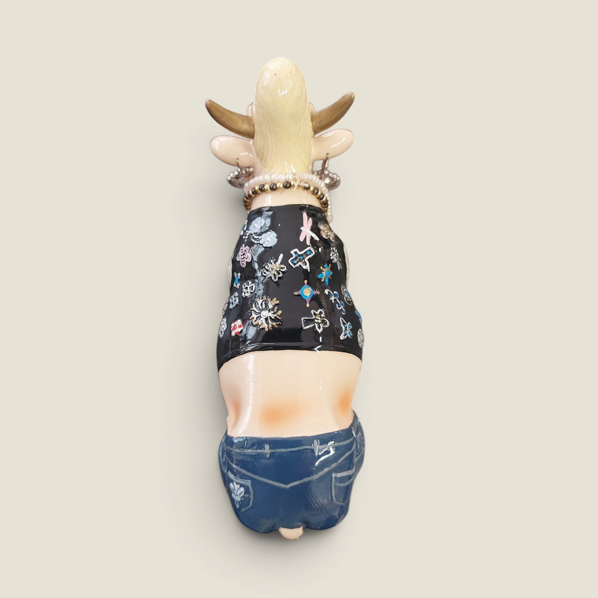 Figurine Depuis des lustres Queen Cow Caesar en résine, vue de dos montrant le crop top noir à motifs et le jean bleu.