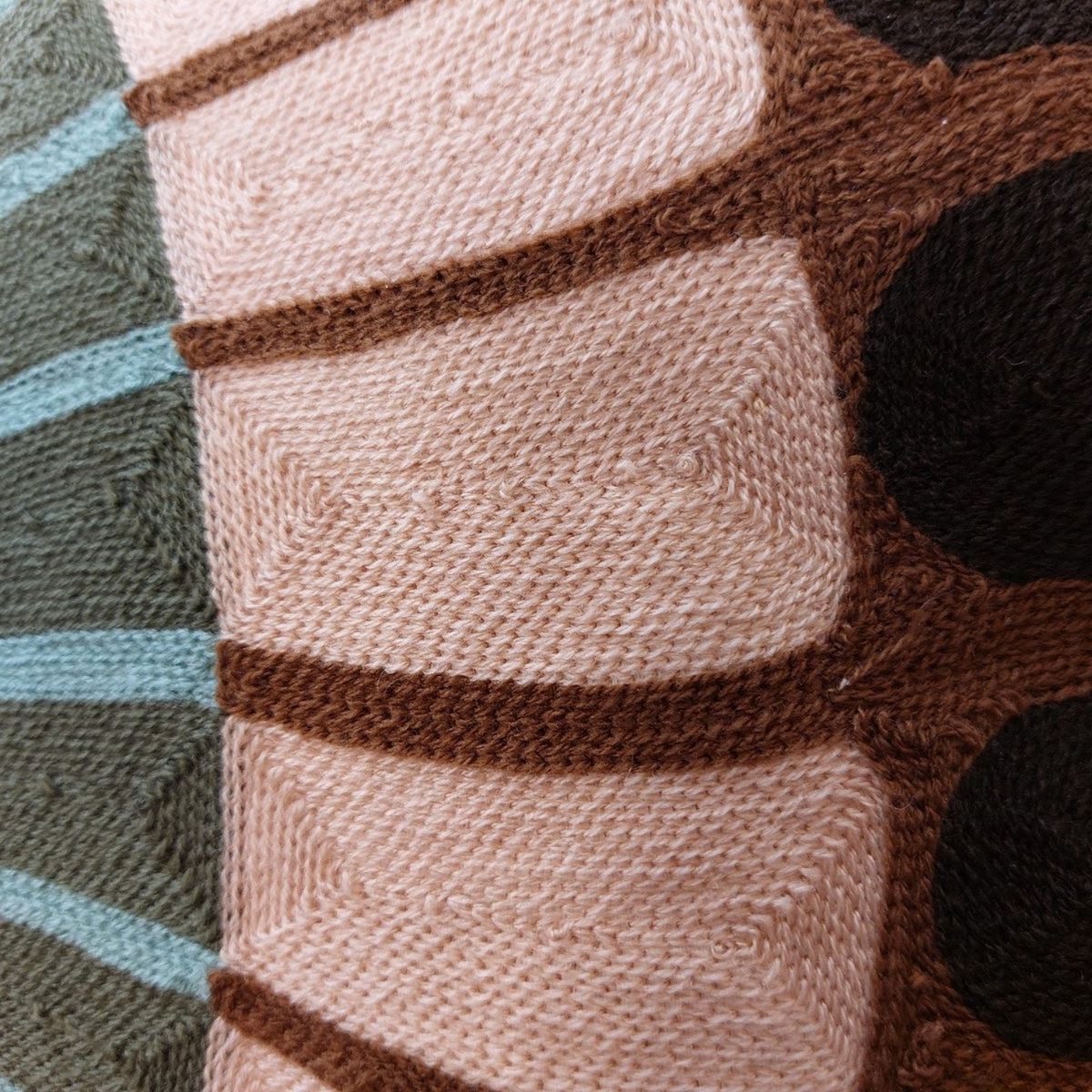 Gros plan sur la broderie artisanale du coussin Depuis des lustres Zeno Forêt aux motifs circulaires vert et beige