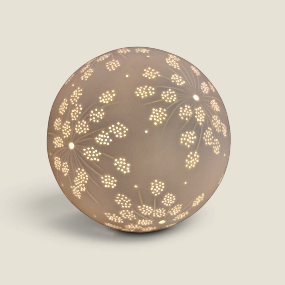 Lampe boule en céramique Depuis des lustres blanc cassé avec motifs floraux ajourés diffusant une lumière douce