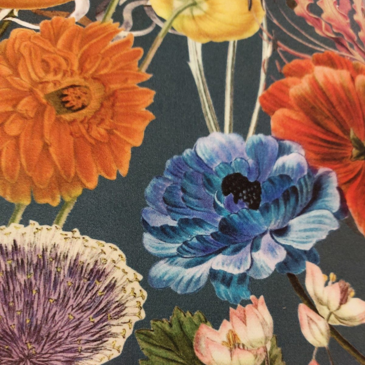 Gros plan sur le motif botanique floral du coussin Depuis des lustres en velours bleu canard avec fleurs colorées