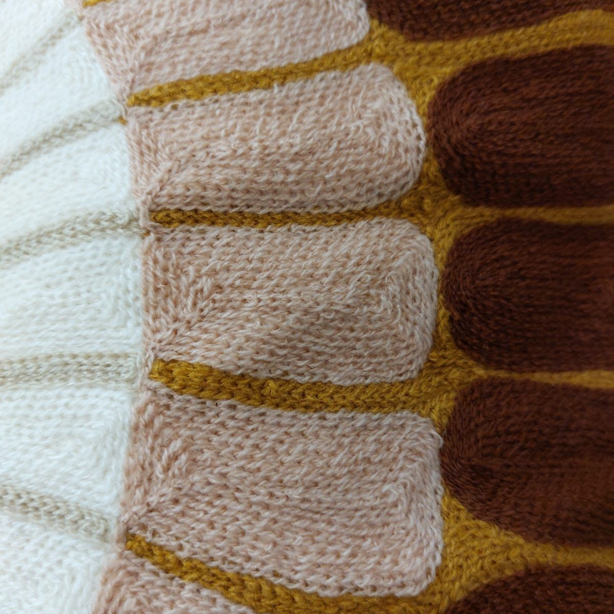 Gros plan sur le coussin brodé Depuis des lustres aux motifs mandala en relief dans des tons terracotta et ocre.