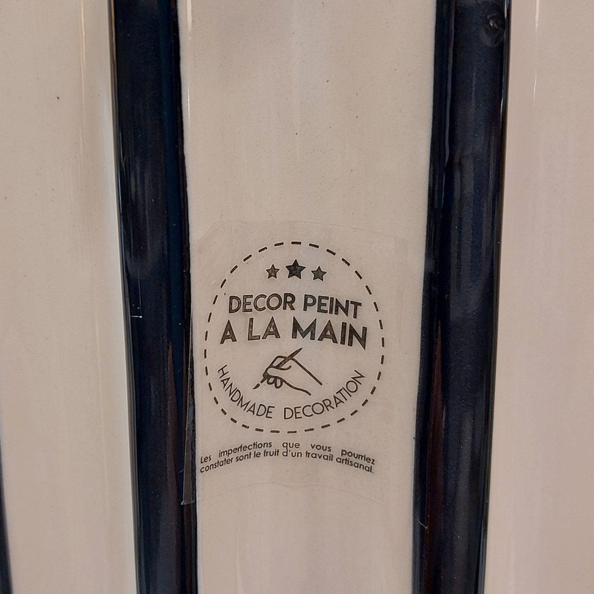 Gros plan sur le vase Depuis des lustres en céramique rayée noir et blanc avec étiquette décor peint à la main
