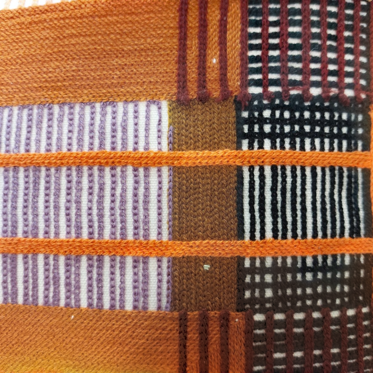 Gros plan sur le coussin Depuis des lustres KAEL aux motifs géométriques ethniques multicolores et textures tissées.