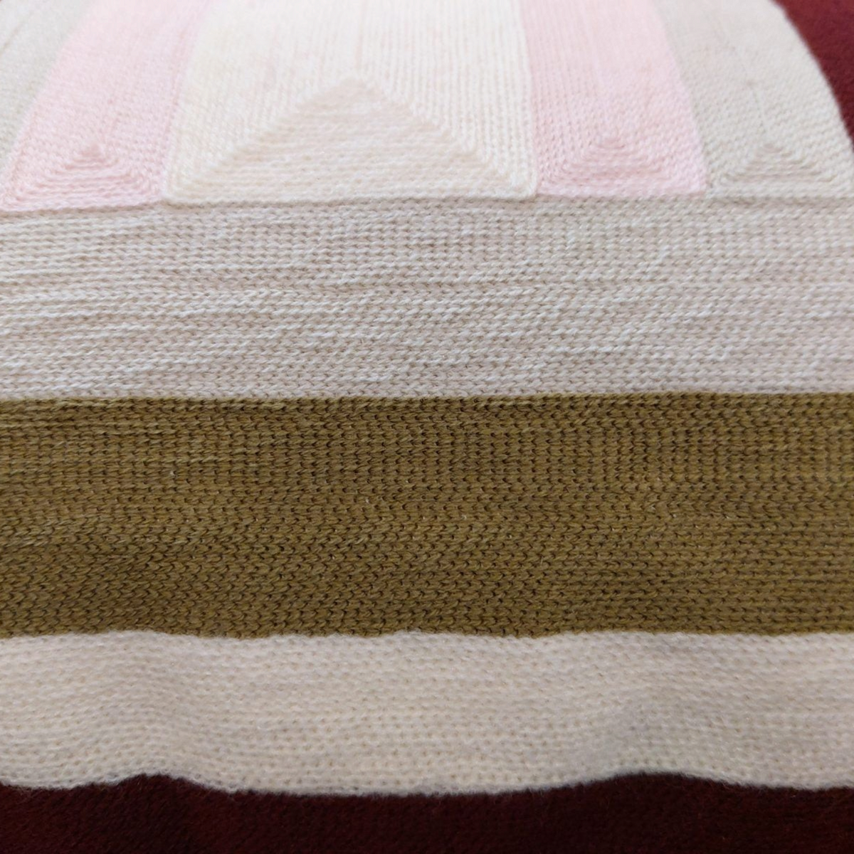 Gros plan sur le coussin brodé Jason de Depuis des lustres, motif géométrique rayé en tons kaki, beige et bordeaux.