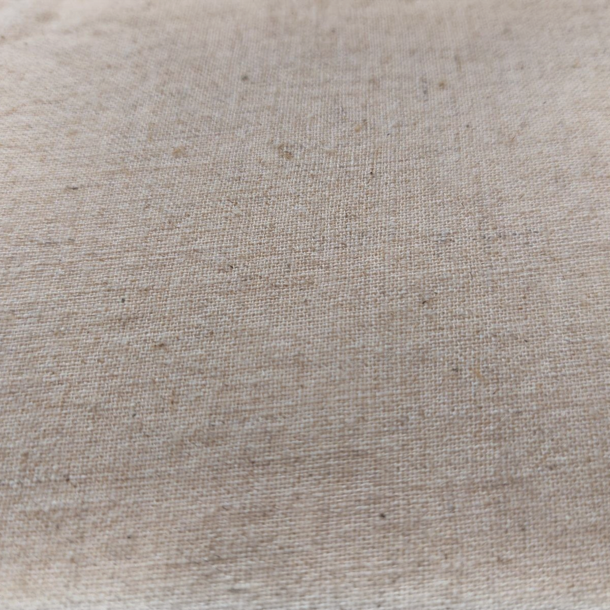 Gros plan sur le revers en lin naturel brut du coussin TAHO de la marque Depuis des lustres, texture tissée beige.