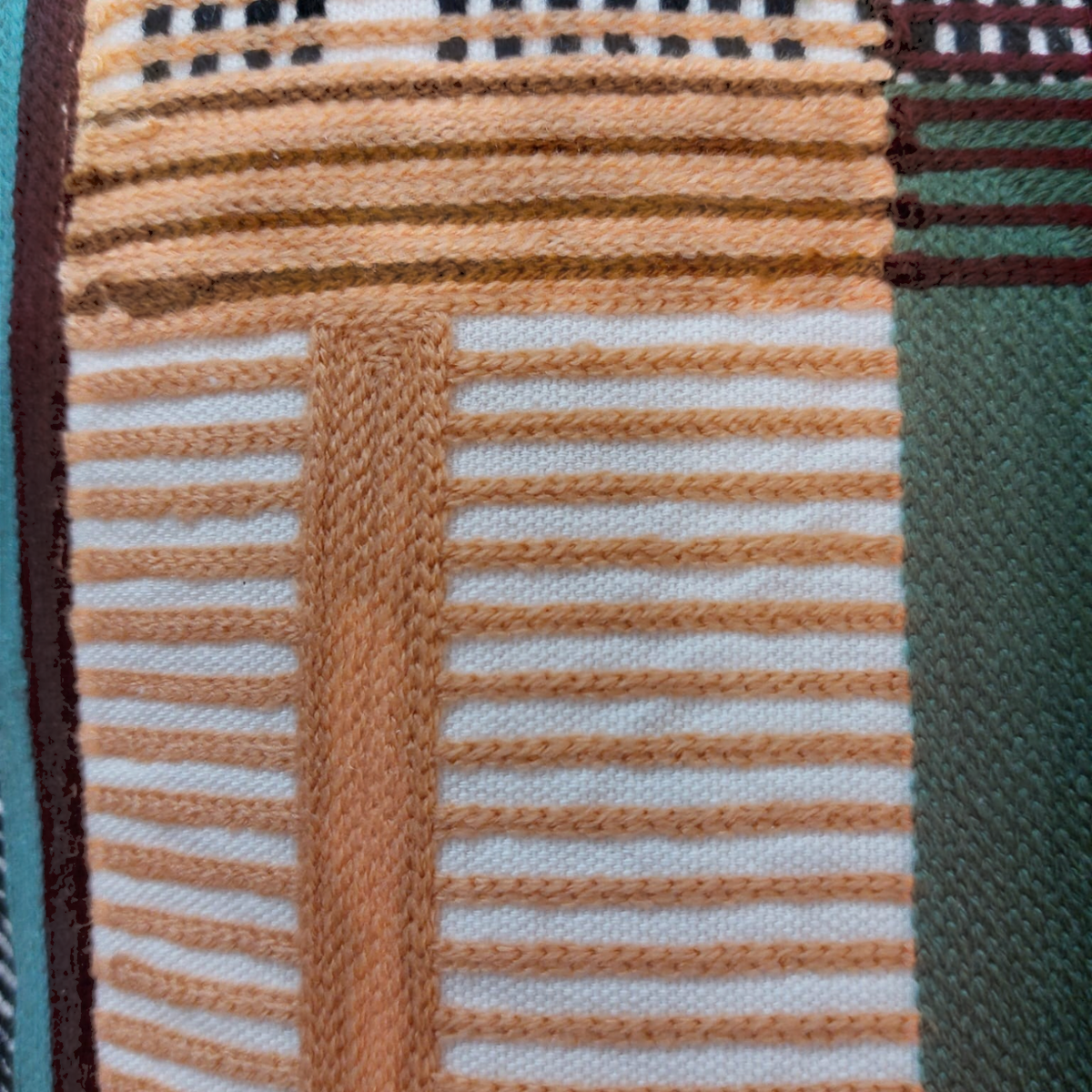 Gros plan sur les broderies multicolores et les motifs géométriques du coussin carré Depuis des lustres KAEL