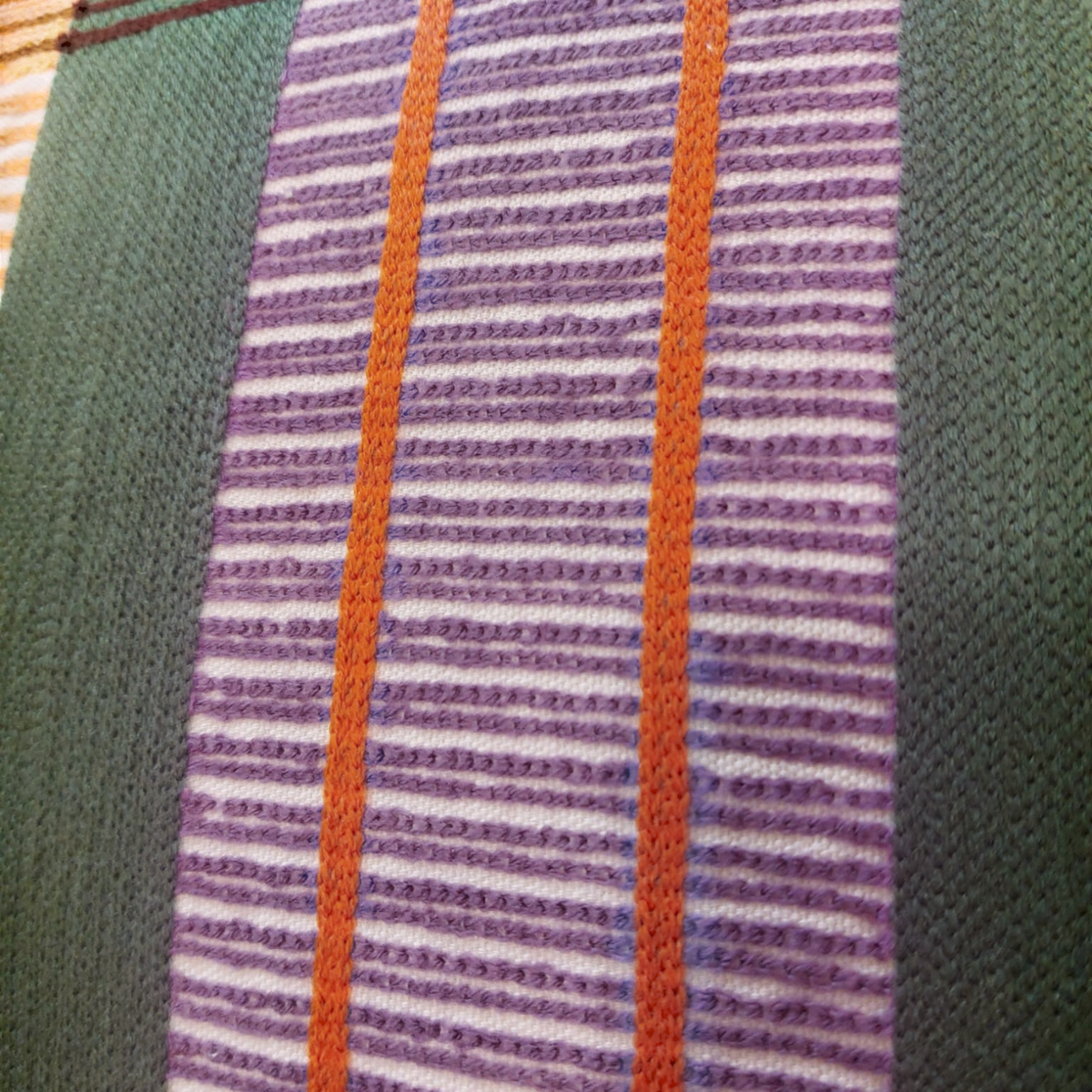 Gros plan sur le coussin brodé multicolore KAEL de Depuis des lustres avec ses rayures texturées et ses détails orange