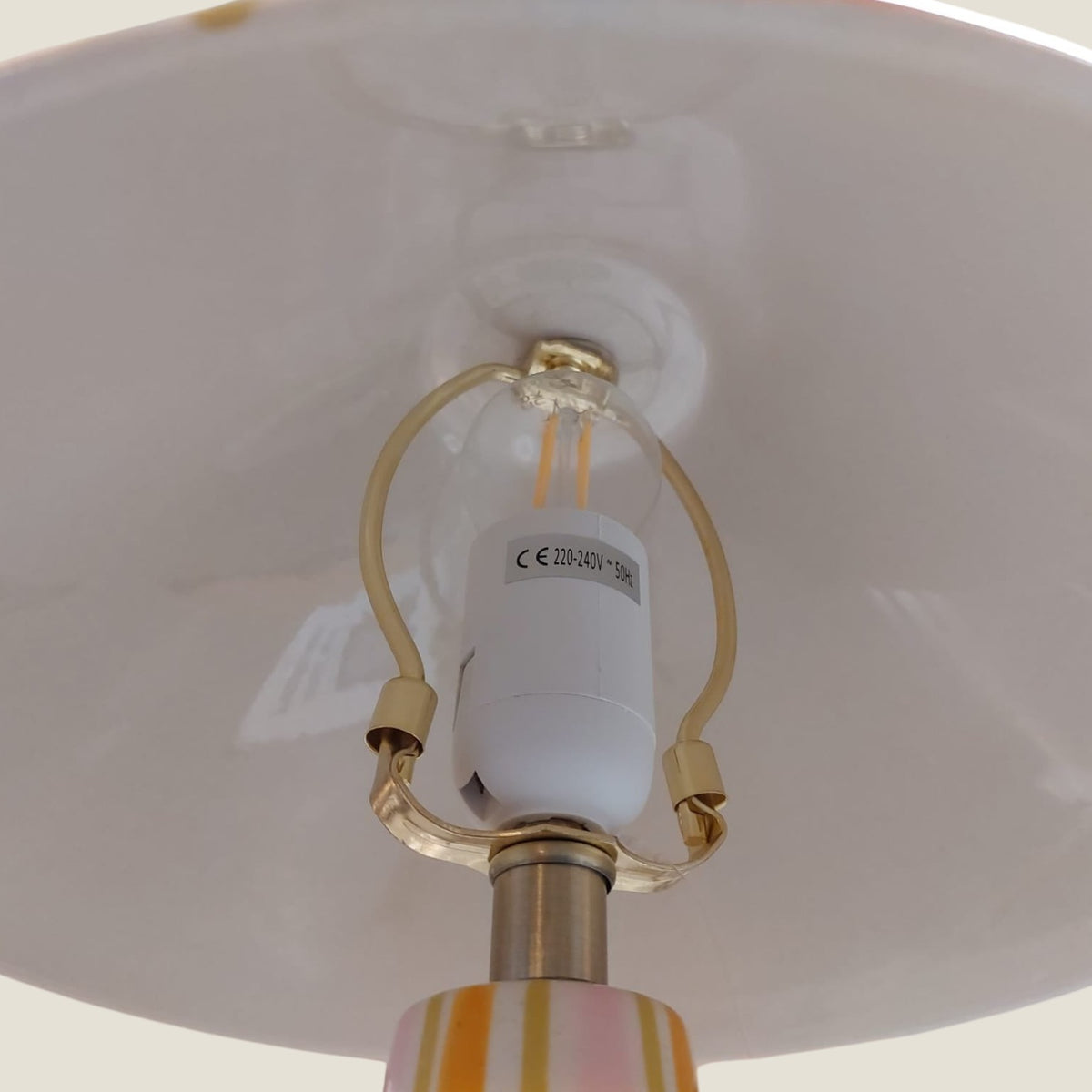 Depuis des lustres Zélie table lamp with striped pink, orange, and gold ceramic base and white interior shade detail