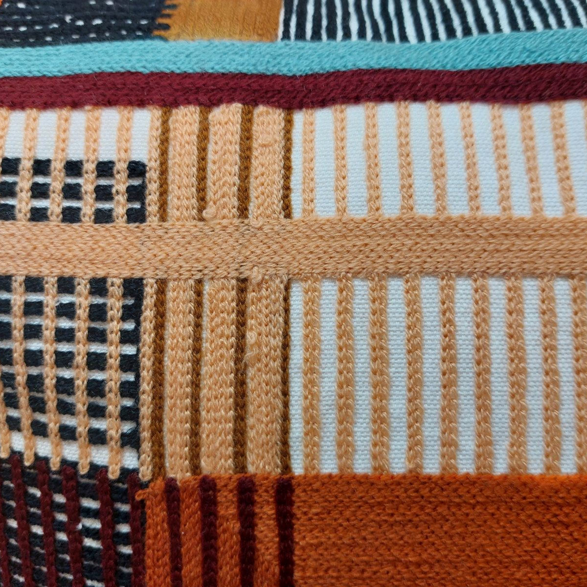 Gros plan sur le coussin Depuis des lustres KAEL avec ses motifs géométriques ethniques aux couleurs vives et texturées